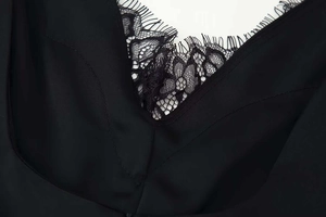 Dettaglio dell'elegante scollo a V con delicato pizzo nero su tessuto di raso lucido