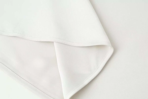Détail de la couture fine et de l'ourlet sur une robe en satin blanc avec dentelle
