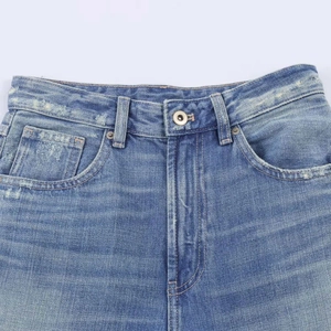 Close-up of high waist blue denim jeans with metal button and frayed vintage details