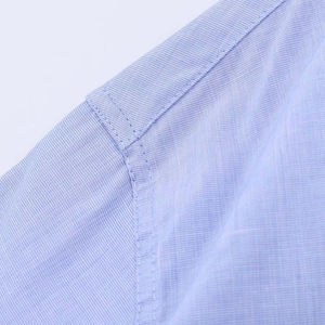 Detail shot of light blue pinstripe shirt showing precise shoulder stitching and fabric texture