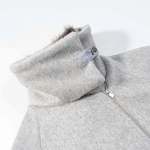 Détail du col en peluche grise avec sangle violette et boucle métallique sur la veste