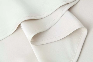 Gros plan des coutures fines et des détails de l'ourlet sur une robe en satin et dentelle