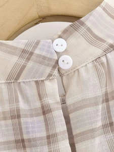 Close-up of beige plaid top featuring dual button back closure and premium linen texture