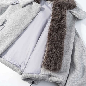 Détail de la veste en laine grise avec col en fourrure marron et fermeture éclair métallique