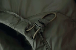 Detailed close-up of olive green down jacket drawstring toggle and matte fabric texture