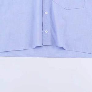 Detailed close-up of light blue shirt showing white buttons and fine fabric texture