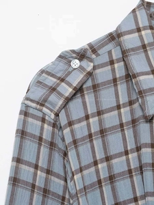 Detail view of plaid shirt dress shoulder with buttoned strap and classic check pattern