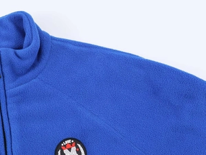 Close-up of blue fleece jacket featuring a high collar and decorative chest patch