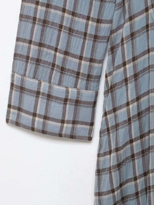 Detailed close-up of blue plaid cotton fabric with wide cuff stitching on the sleeve