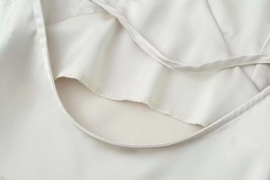 Vue détaillée de la bretelle en satin blanc et des coutures sur l'encolure