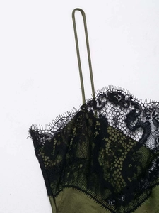 Detail shot of green satin dress featuring black eyelash lace trim and thin straps