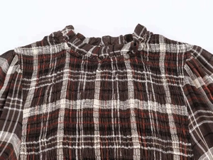 Dettaglio camicia a quadretti marrone con petto a nido d'ape e colletto alla coreana arricciato