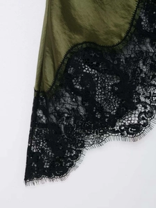 Close-up of olive green satin dress featuring intricate black floral eyelash lace trim