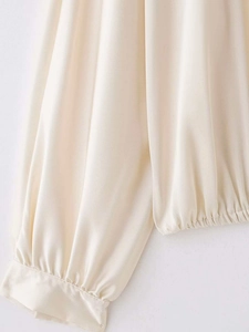 Détail de manches lanternes élégantes avec poignets élastiques sur une blouse en satin beige