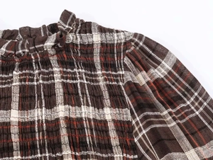 Dettagli della camicia da donna a quadretti con trama a punto smock e collo a volant