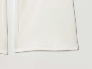 Dettaglio dell'orlo dei pantaloni bianchi a zampa con cuciture precise e tessuto premium