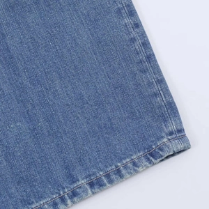 Detailed close-up of blue denim hem featuring twill weave and washed faded edges