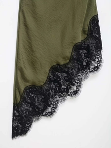 Detail of olive satin dress featuring black eyelash lace trim and asymmetric hemline