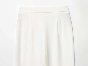 Dettaglio dei pantaloni bianchi a vita alta con trama in tessuto fine e fascia larga