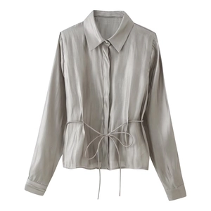 Detail of silver grey satin shirt showing lustrous silk-like fabric and waist tie