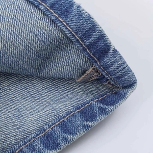 Detailed close-up of blue denim fabric with high-quality yellow contrast stitching details