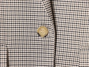 Detail of vintage brown houndstooth wool fabric and amber resin button on blazer