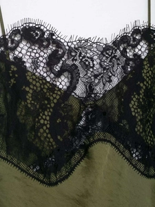 Detail of olive green satin dress featuring black eyelash lace trim at the neckline