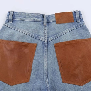 Close-up of high waist blue jeans featuring unique large brown faux leather back pockets
