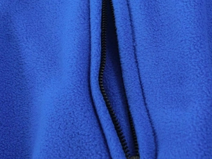 Detailed close-up of soft royal blue fleece fabric texture and black zipper closure