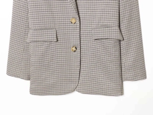Detail of classic brown houndstooth blazer with two buttons and front flap pockets