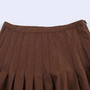 Detailed close-up of brown pleated skirt waistband with invisible side zipper and fabric texture