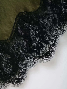 Detail of olive green satin dress featuring exquisite black eyelash lace embroidery edges