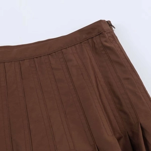 Close-up of the high-waisted pleated midi skirt with a side invisible zipper in brown