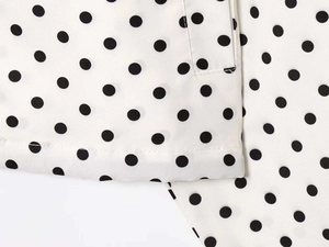 Close-up of white seersucker fabric featuring classic black polka dot pattern and fine stitching