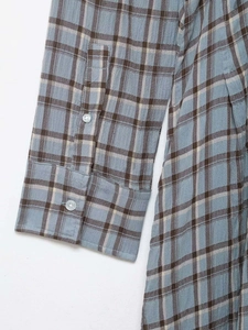 Macro detail of the buttoned cuff on a grey plaid cotton shirt with sharp texture