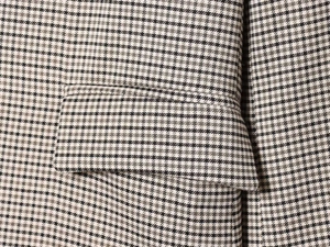 Macro detail of houndstooth plaid fabric and flap pocket on a brown vintage blazer
