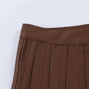Close-up of waist detailing and pleats on a minimalist brown high-waisted midi skirt