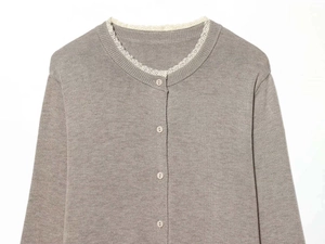 Close-up of the grey-brown knitted cardigan with delicate white lace trim on the neckline
