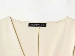 Detail of satin shirt collar with brand label on elegant beige smooth fabric