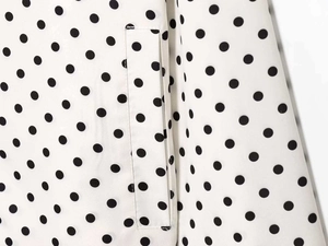 Detail of black polka dot pattern on white fabric with flat pocket design and fine texture