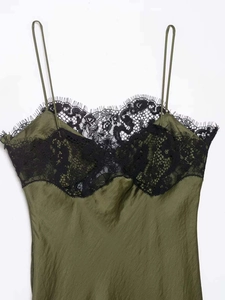 Close-up of dark green satin dress featuring black eyelash lace trim and thin straps