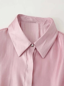 Detail showing the pink satin shirt collar with elegant metallic button and smooth texture