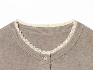 Detail of coffee knit cardigan featuring round neck with cream lace trim and button