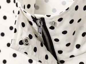 Macro view of metallic zipper and snap button details on the polka dot puffer jacket