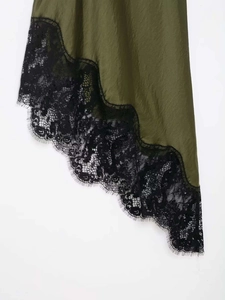 Detail of olive green satin dress featuring black eyelash lace trim and asymmetric hem