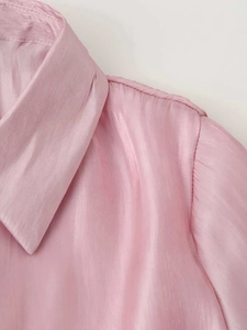 Detail of a pink satin shirt showing the sharp collar structure and shoulder stitching