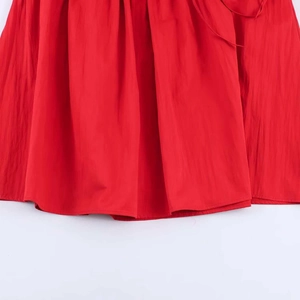 Detail shot of a red midi dress featuring fine pleated texture and fluid drape fabric