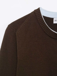 Detail of dark brown knit cardigan showing ribbed crew neck and contrast blue inner tape