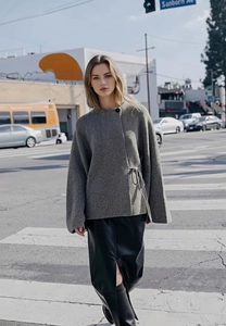 Close-up of the textured grey knit cardigan with unique side-tie and asymmetrical design