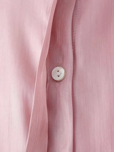 Close-up of pink satin shirt fabric with white button detail and fine texture